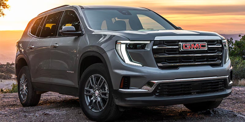 GMC SUV parked on rocky sunset view.