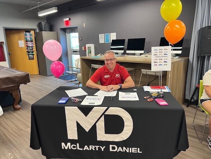 PR employee in red uniform at the McLarty Daniel table for charity event